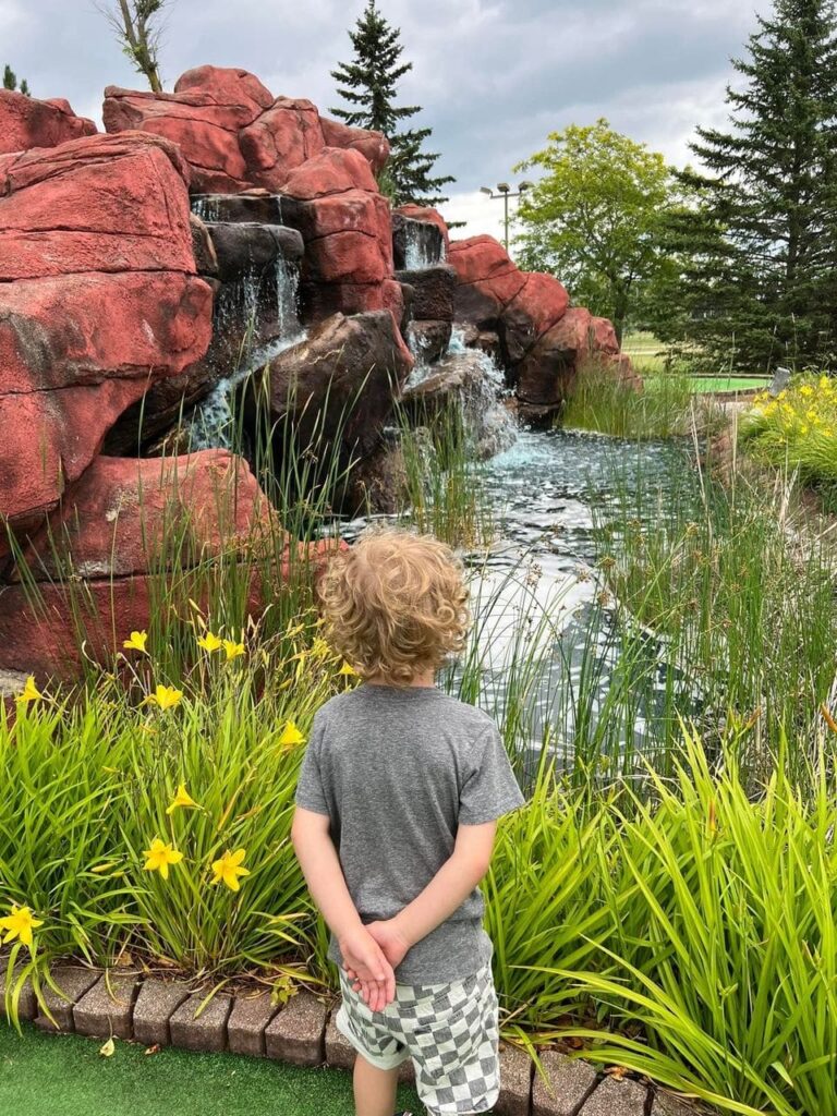 child looking at waterfall at Logger's Park mini golf Richfield Wisconsin