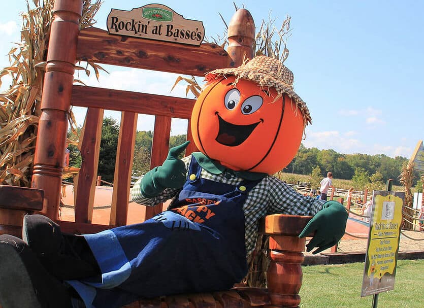 Scarecrow with large pumpkin head sitting in an oversized rocking chair at Basse's Taste of Country.