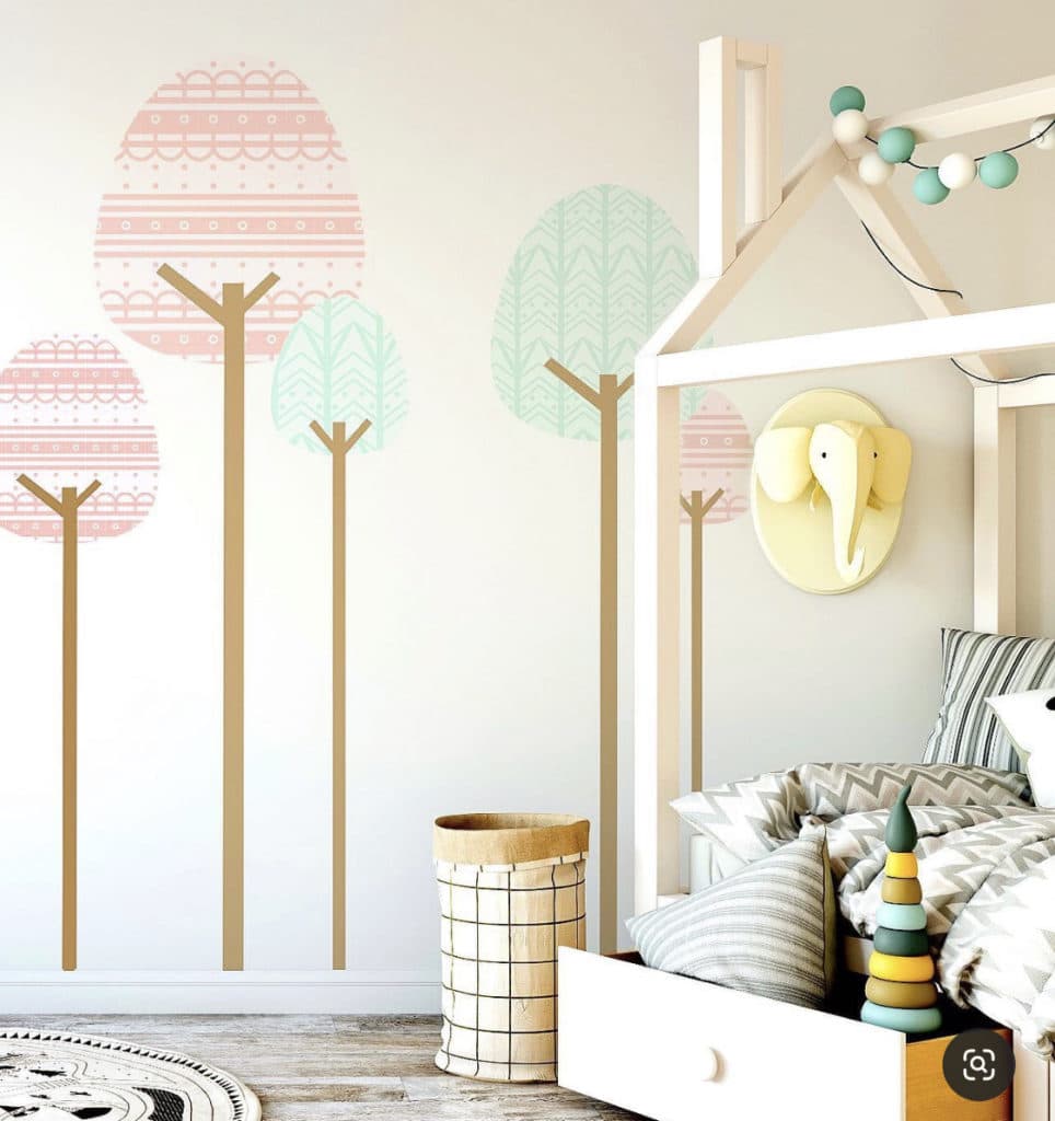 Nature-inspired toddler room with pastel tree decals and a Montessori-style bed frame, ideal for a minimalist aesthetic.