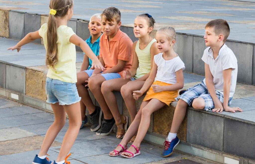 Kids play charades outside.