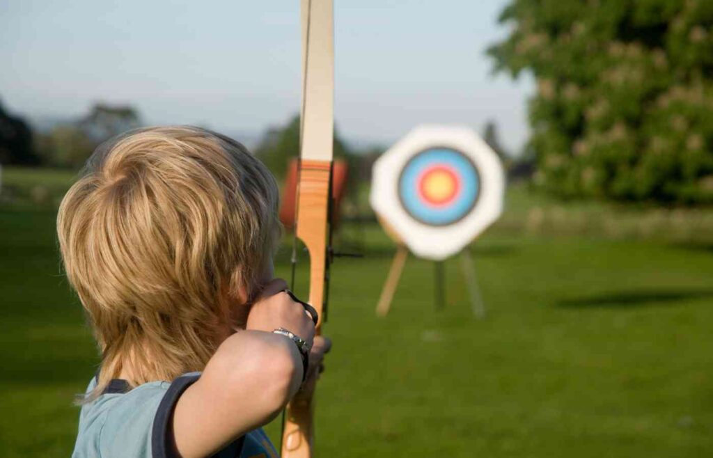 Child using a bow and arrow on an archery range