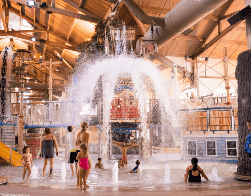 Springs Water Park indoor area featuring large water slides, climbing structures, and splash zones under a wooden-beam ceiling at The Ingleside Hotel near Milwaukee.