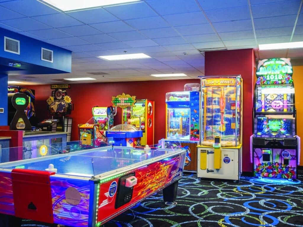 Brightly lit arcade area at Springs Water Park, featuring air hockey, arcade games, and claw machines for family entertainment.