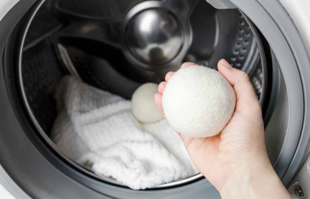 Wool dryer balls being places in  dryer with a blanket