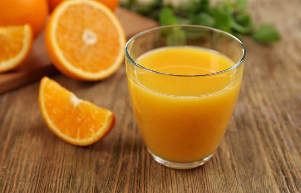 Glass of orange juice with slices oranges.