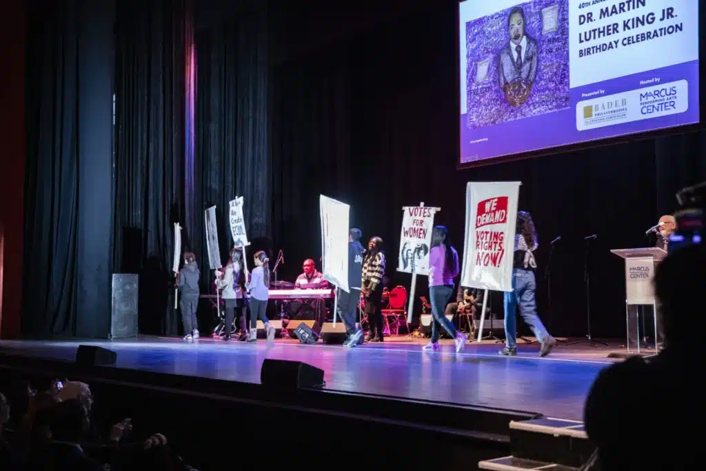 young contestants stand on stage next to their art content entries