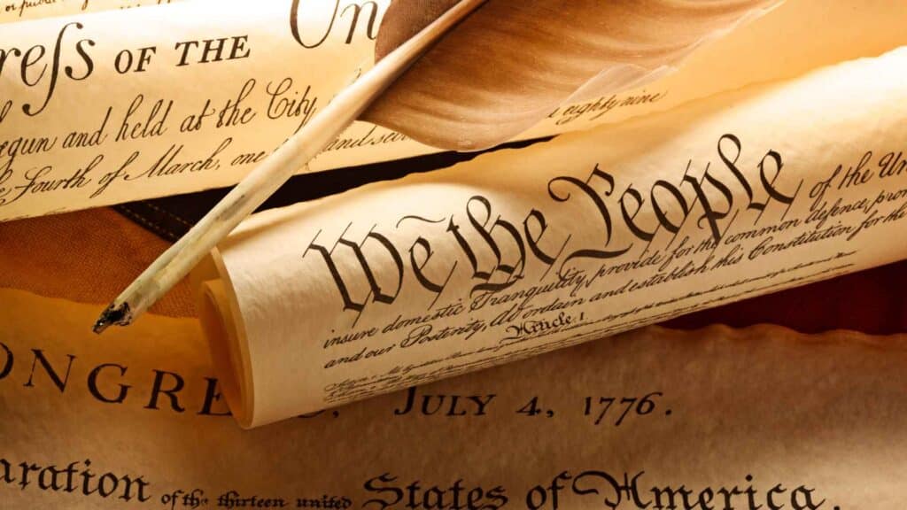 Scroll with the constitution of the united state of america reading We The People in cursive handwriting.