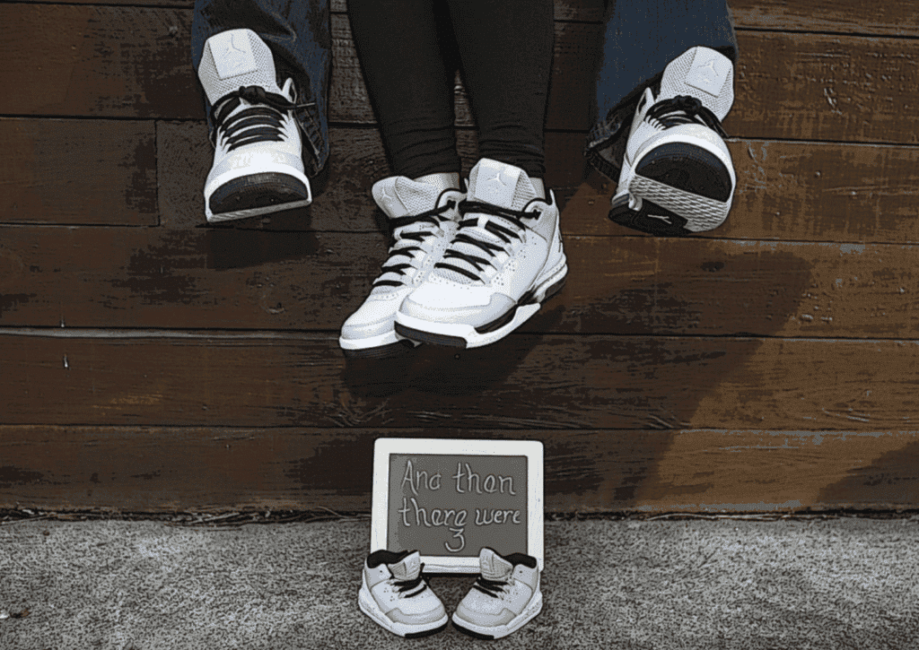 A pair of adorable baby shoes is placed on a textured surface, serving as a creative pregnancy announcement. 