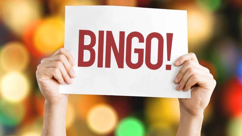 Child holding up sign that say Bingo! in red letters