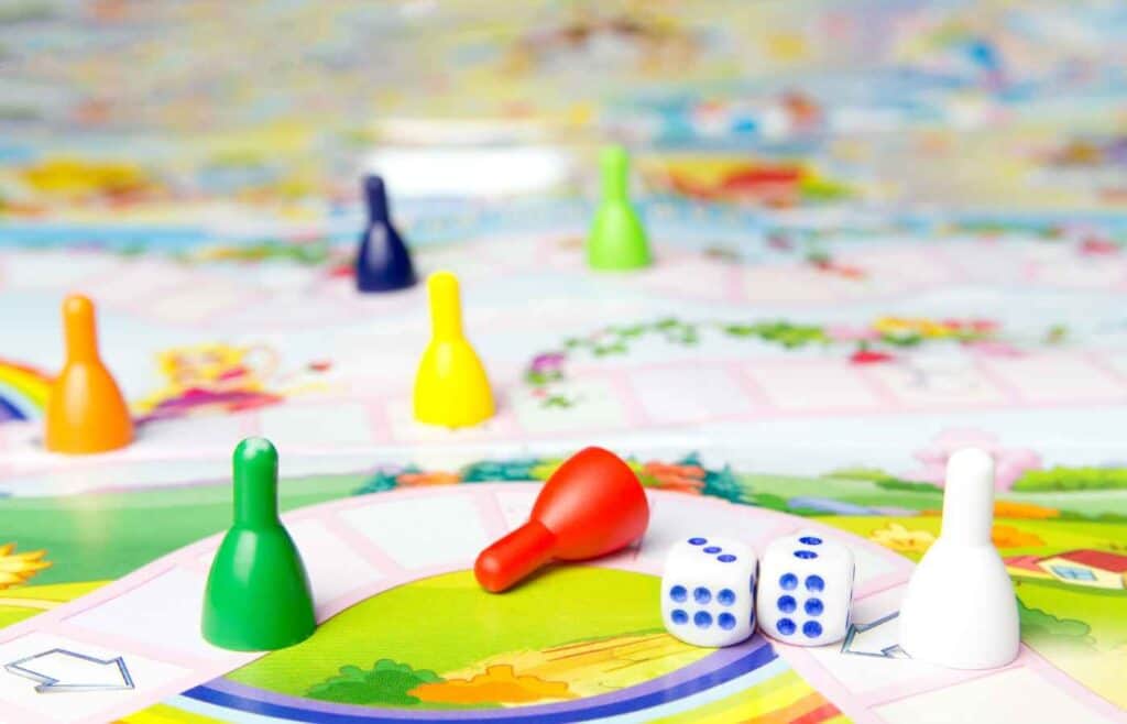 A Candy Land board game is laid out, showcasing its colorful, winding path filled with vibrant spaces in shades of red, blue, yellow, green, and purple. 