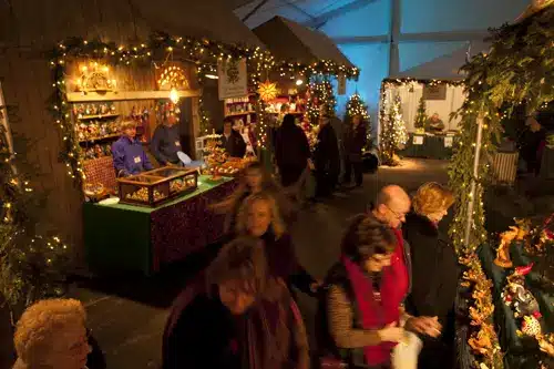 Visitors shopping at festively decorated booths at the Old World Christmas Market at The Osthoff Resort, surrounded by twinkling lights and handcrafted holiday goods.