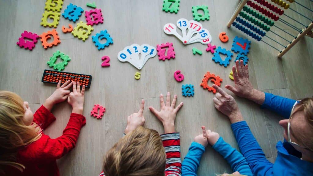 Little kids counting by twos with their teacher using manipulatives, their fingers, and colorful numbers.