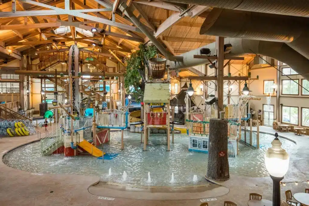 Springs Water Park indoor area featuring large water slides, climbing structures, and splash zones under a wooden-beam ceiling at The Ingleside Hotel near Milwaukee.