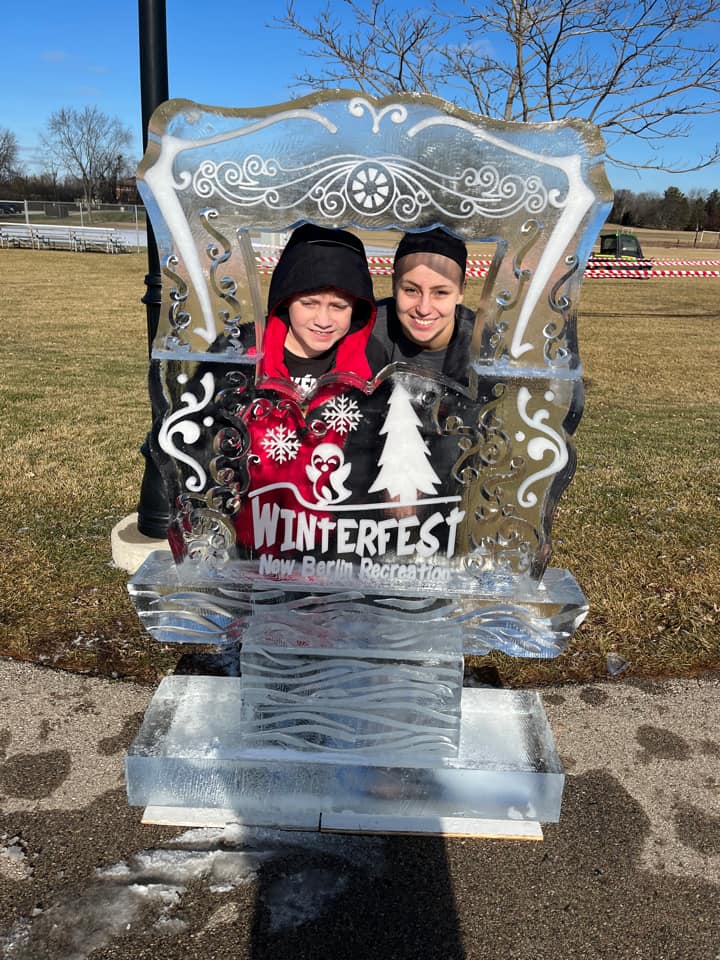 Woman and young boy pose behind winter fest ice sculpture 