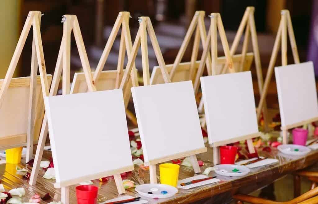 Blank canvases on easels set up for a kids' paint and sip birthday party with creative painting stations