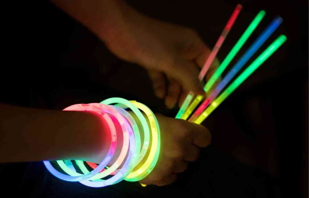 Hands holding colorful glow sticks, perfect for a glow stick dance party at a kid's birthday celebration