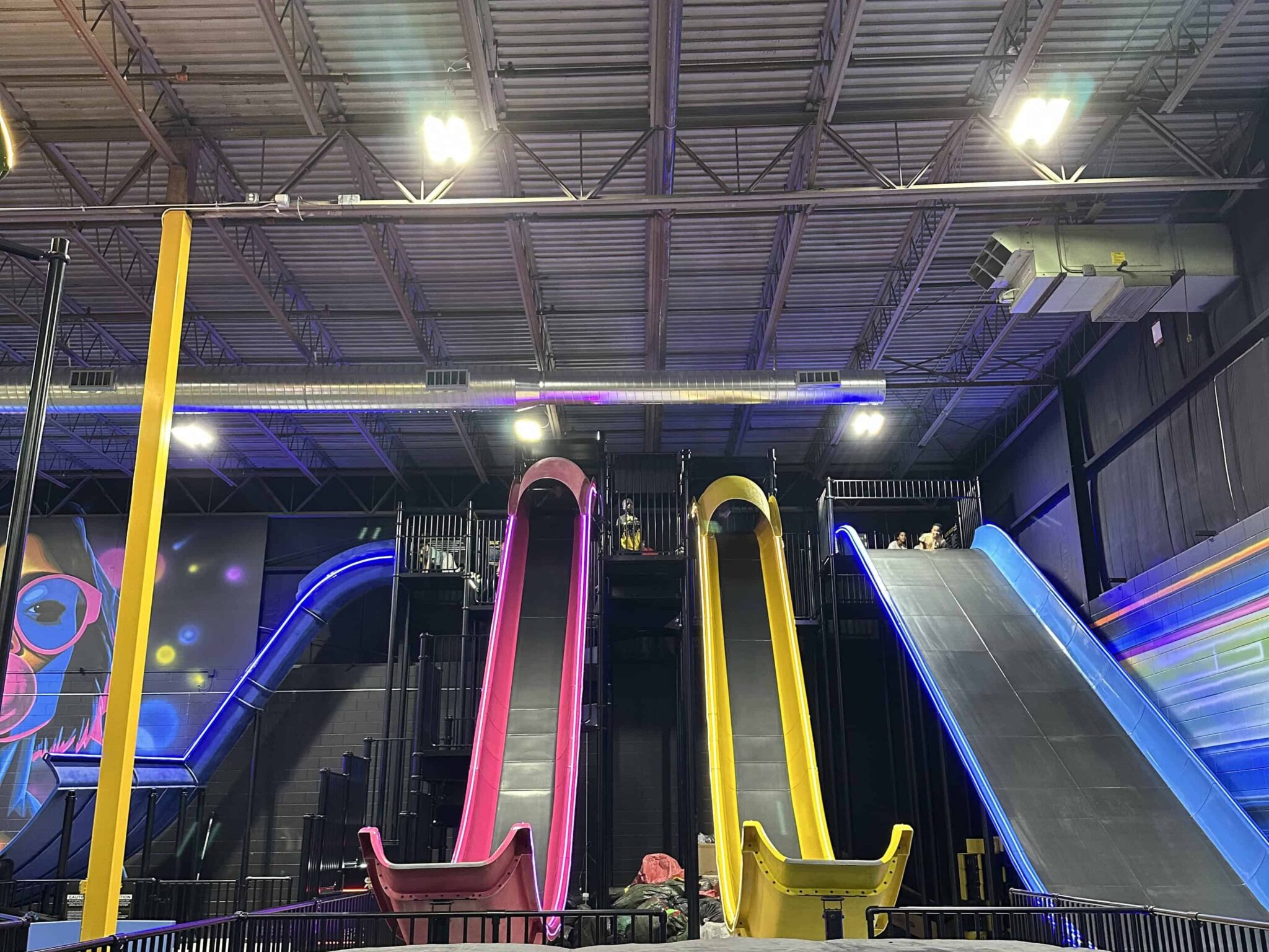 Four towering slides in bright pink, yellow, and blue at Slick City Action Park, inviting thrill-seekers of all ages.