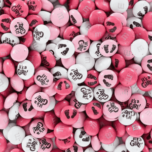 A close-up of pink and white, personalized M&Ms scattered across a surface.