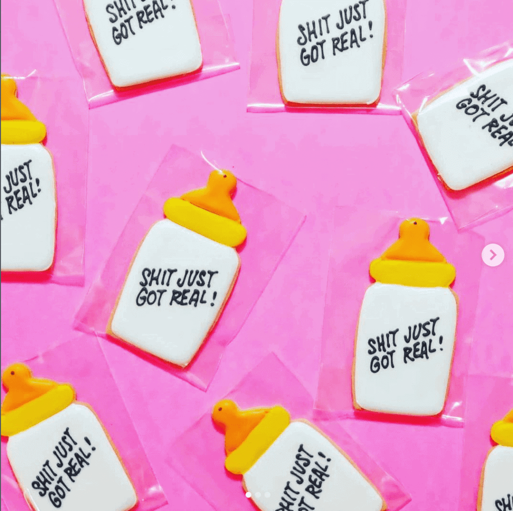 Pregnancy Announcement Cookies that say "Shit Just Got Real" on a baby bottle.