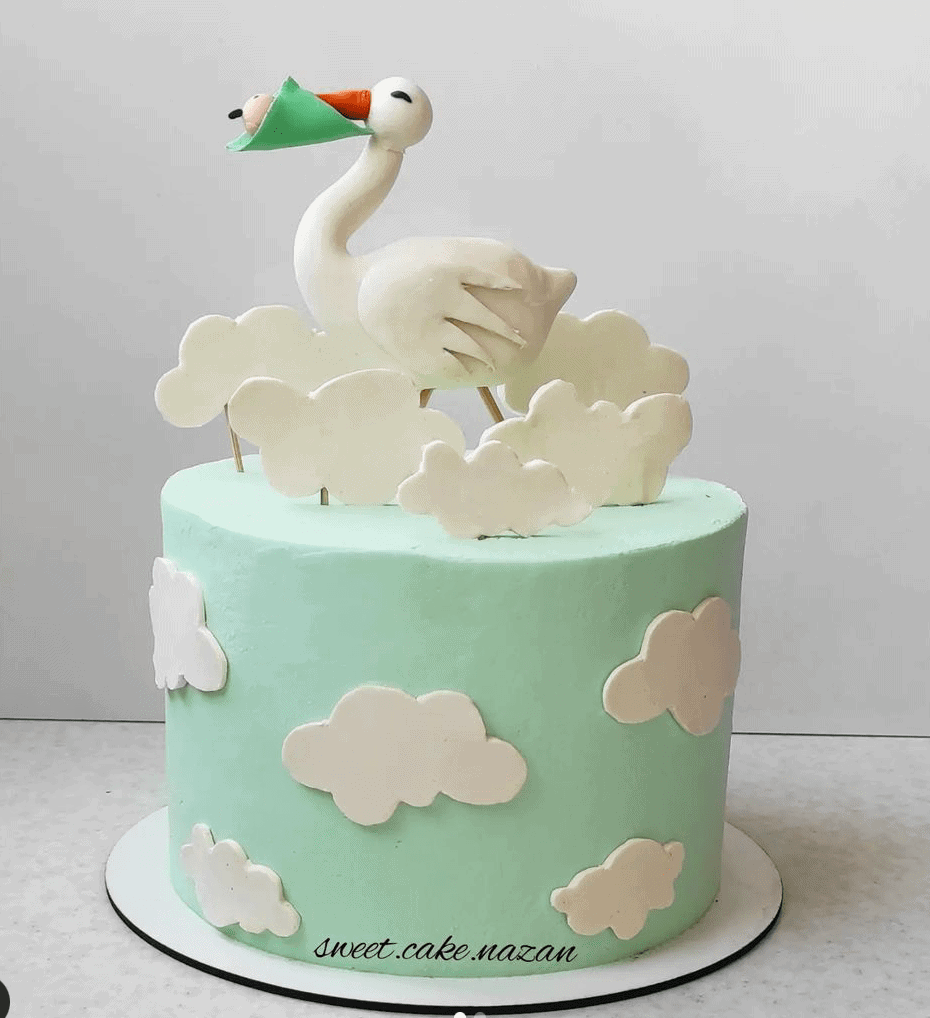 A beautifully decorated cake designed for a pregnancy announcement, featuring a charming stork delivering a baby. 