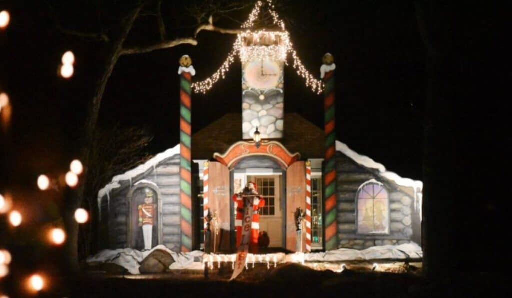 Santa's lakeside cabin at the Santa Cruise destination, decorated with lights and toy soldier figures, as Santa greets visitors from the doorway.