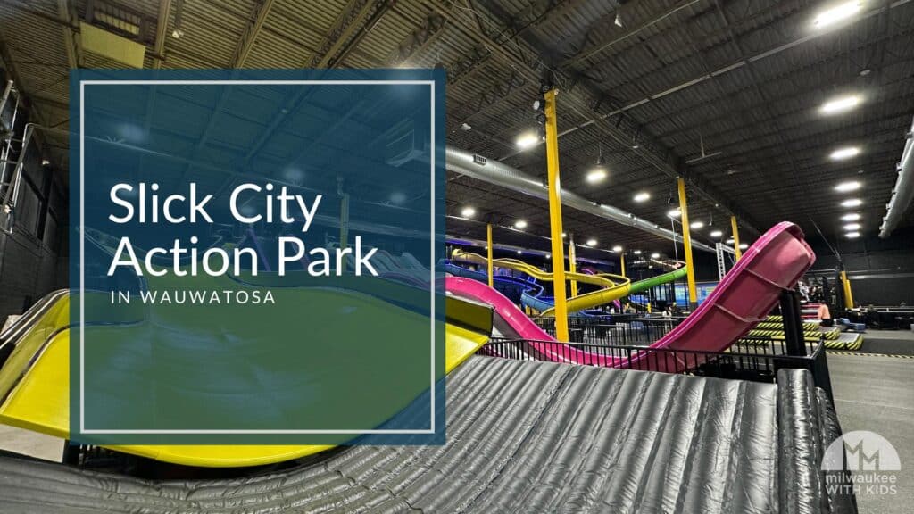 Wide view of colorful slides at Slick City Action Park in Wauwatosa, featuring bright pink, yellow, and green slides under a high industrial ceiling.