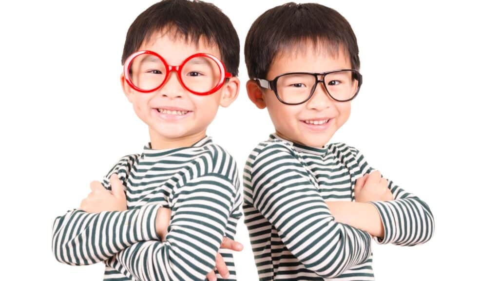 Two boys dressed up in matching outfits: black and white striped shirts and glasses.