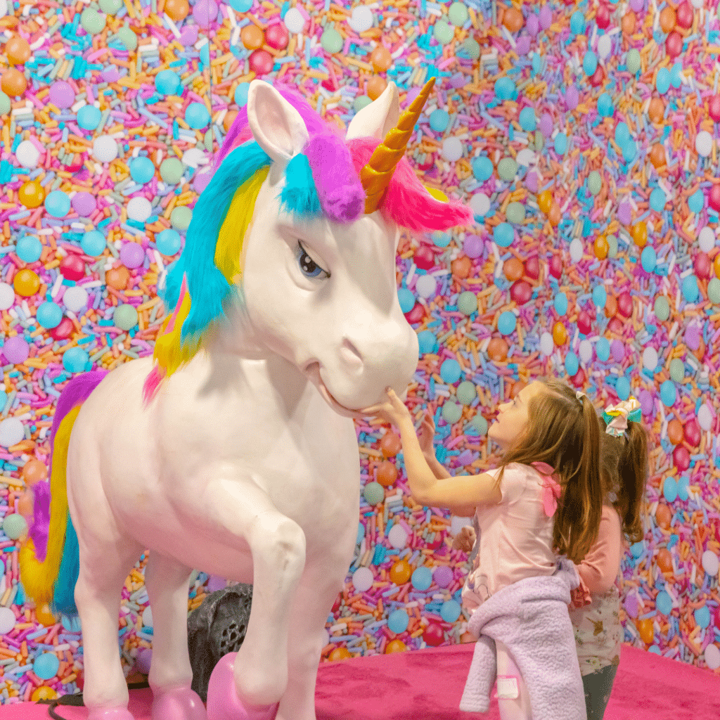 Young girls play with unicorn statue