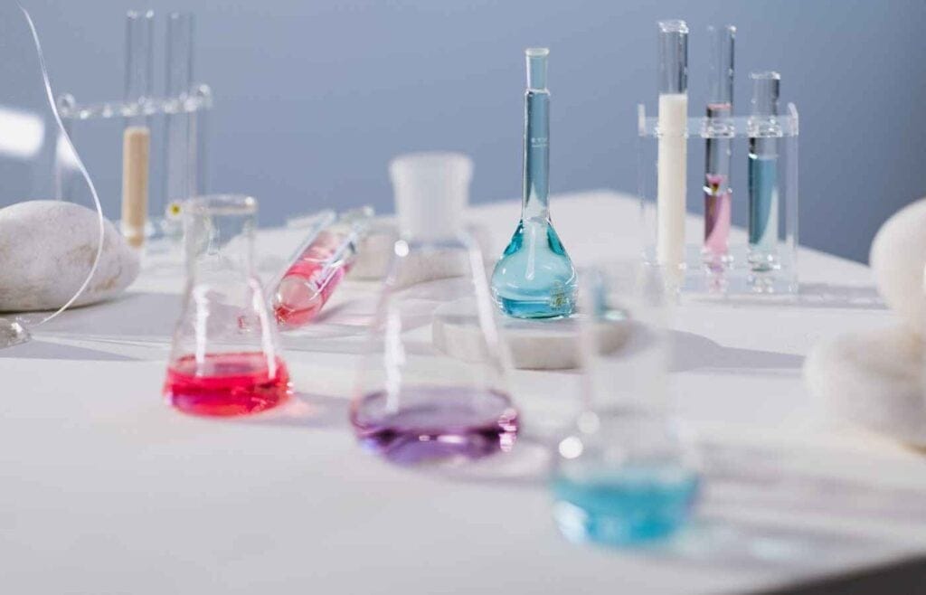 Glass beakers with colorful liquid solutions in a chemistry lab setting, symbolizing experiments and learning in chemistry.