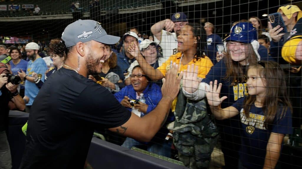 Young fans and adult fans high five brewers player excitedly 