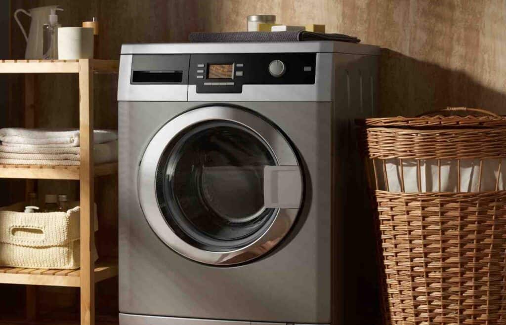 A front-loading washing machine with a clear circular glass door, offering a view of the drum inside. The machine has a sleek, modern design.